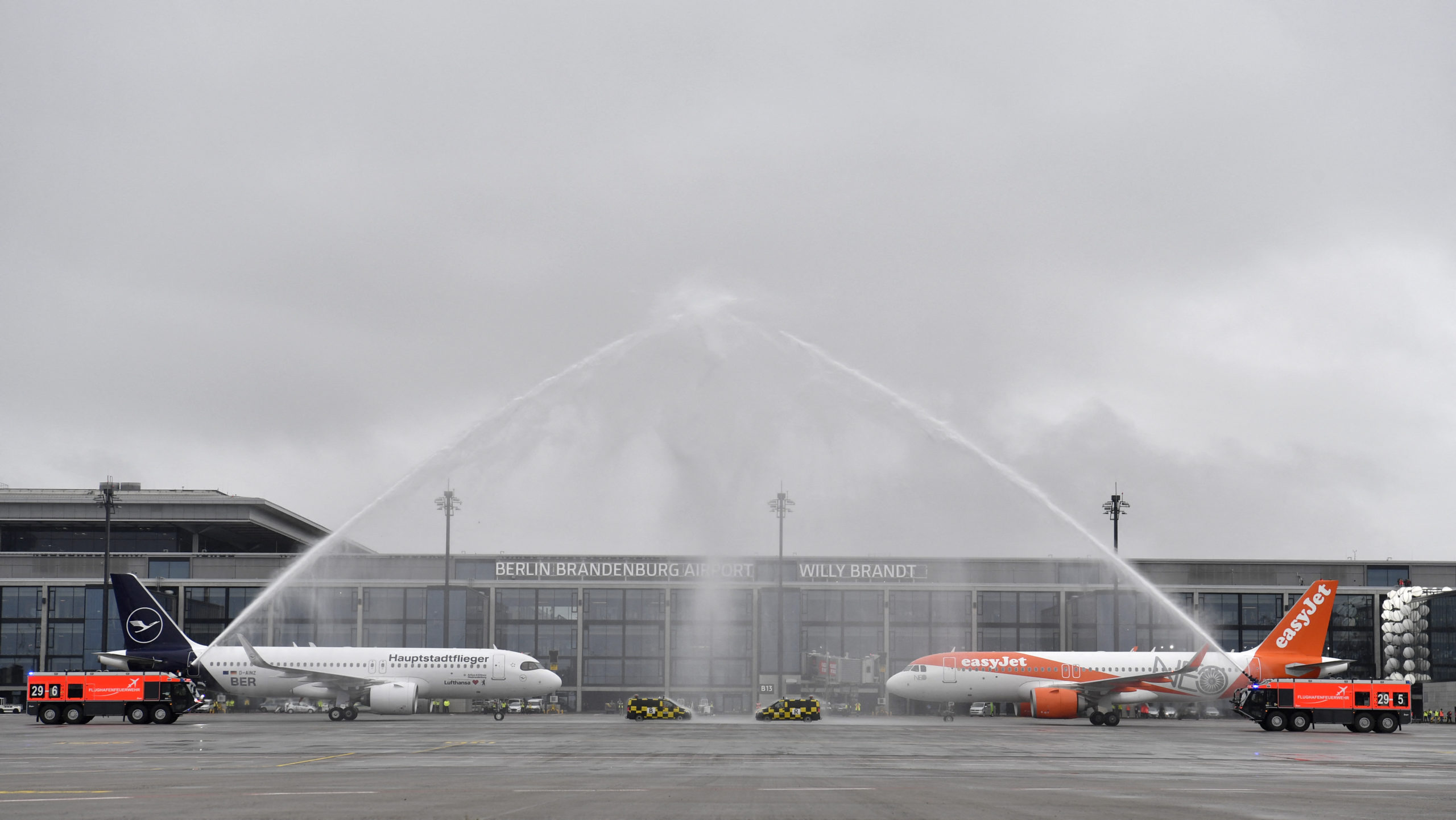 Fire engines spray water to greet planes of airlines Lufthansa (L) and Easyjet, the first ones to arrive at Berlin's airport "Berlin Brandenburg Airport Willy Brandt", during the opening ceremony, in Schoenefeld, southeast of Berlin, on October 31, 2020. - Passenger flights are to begin landing on October 31, 2020 at Berlin's new international airport, a moment many Germans thought they might never see after years of embarrassing delays and spiralling costs.