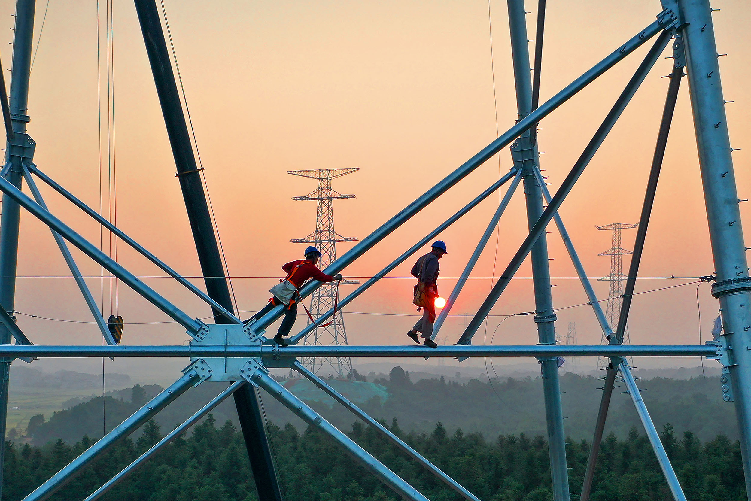 This photo taken on September 28, 2021 shows employees working on high voltage transmission tower in Yichun, in China's central Jiangxi province. (Photo by STR / AFP) / China OUT