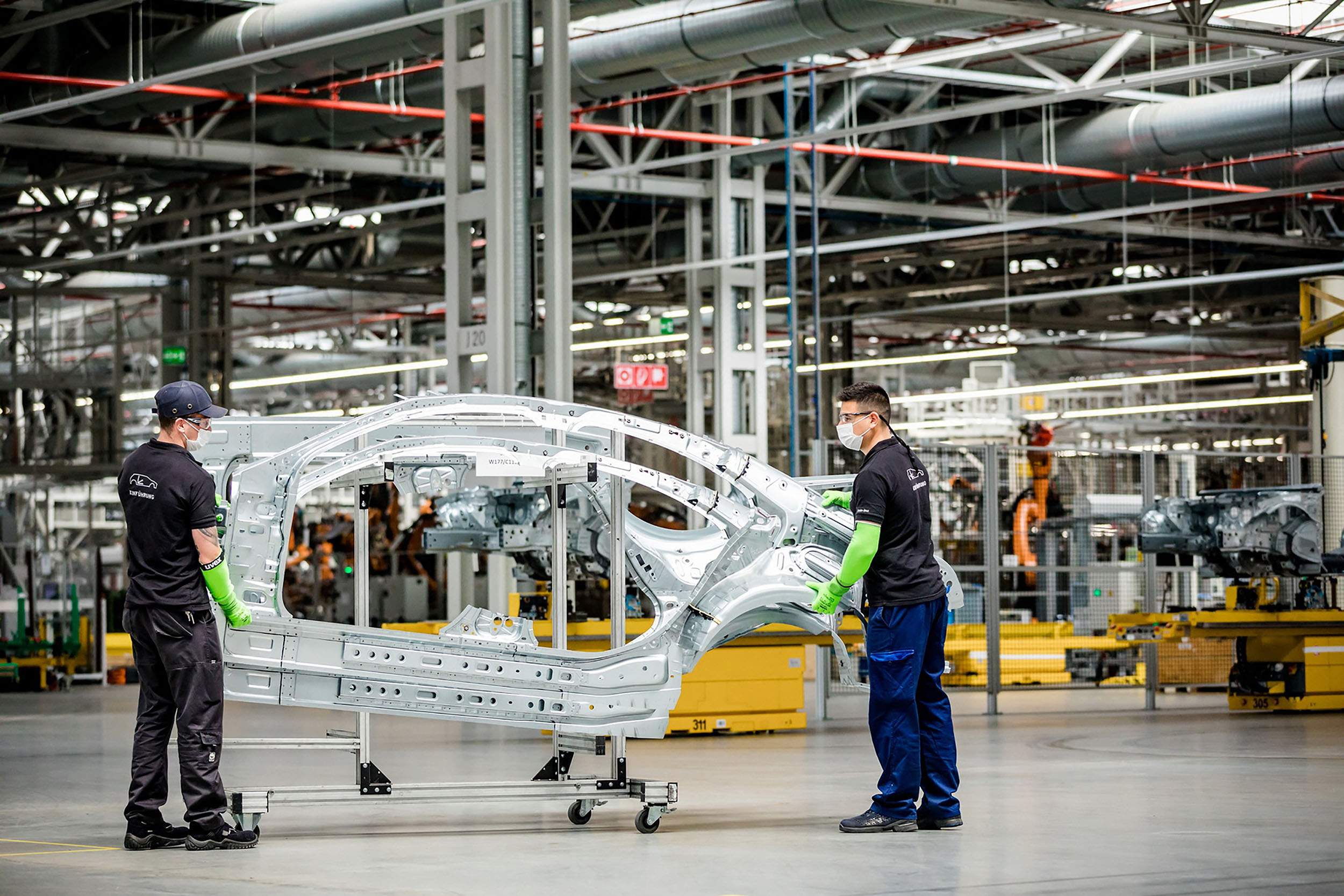 In this handout picture released on April 28, 2020 by the Mercedes-Benz factory in Kecskemet, Hungary, employees wearing their protection masks prepare a frame of a car body in the factory of German car maker Mercedes-Benz on March 24, 2020. - Hungarian factory of Mercedes restarted operations at its plant on April 28, 2020. The production was suspended in middle of March here amid the new coronavirus COVID-19 pandemic. (Dudar SZILARD / AFP)