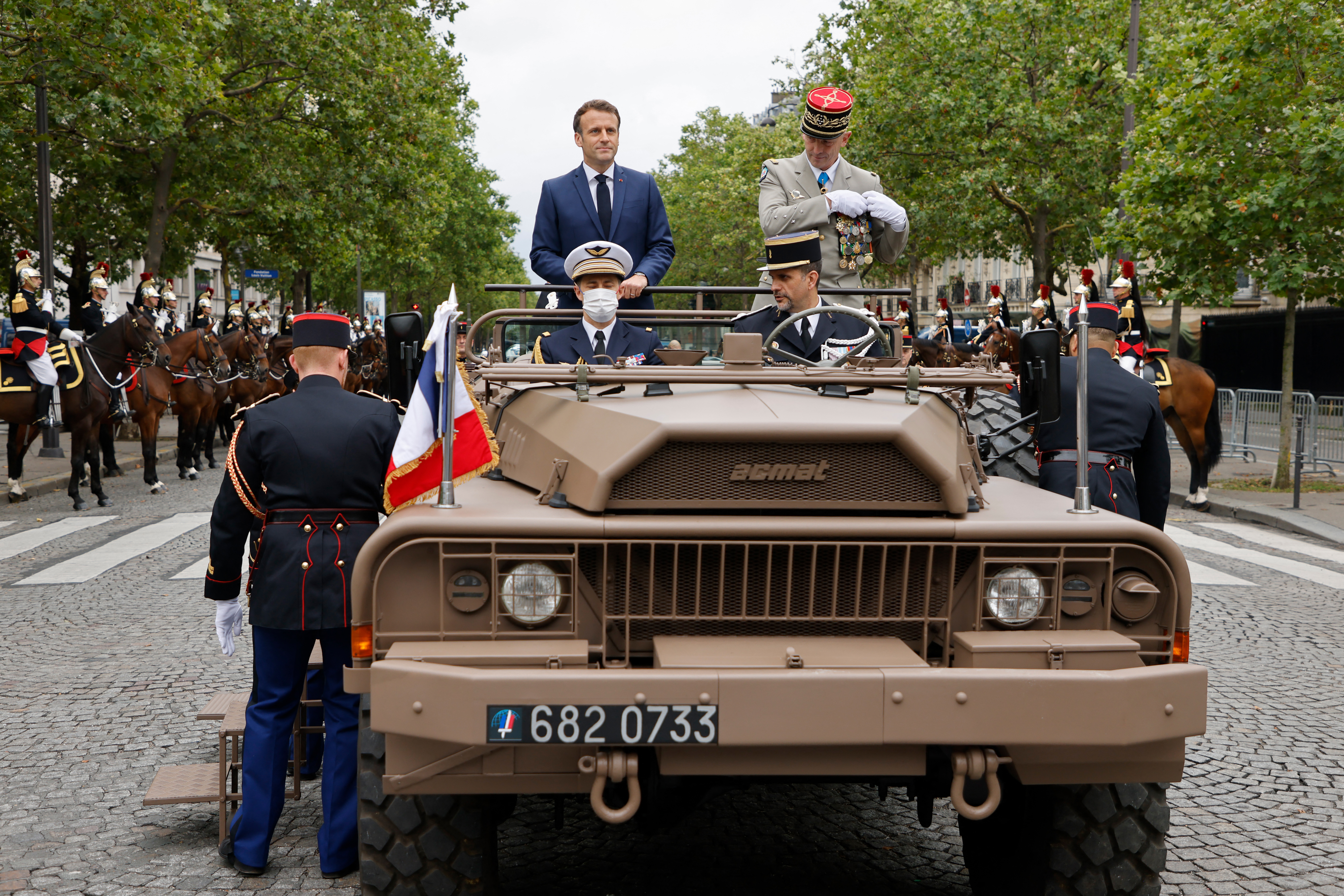 French President Emmanuel Macron and French Armies Chief of Staff General Francois Lecointre stand in the command car prior to review troops during the annual Bastille Day military parade on the Champs-Elysees avenue in Paris on July 14, 2021. (Photo by Ludovic MARIN / POOL / AFP)